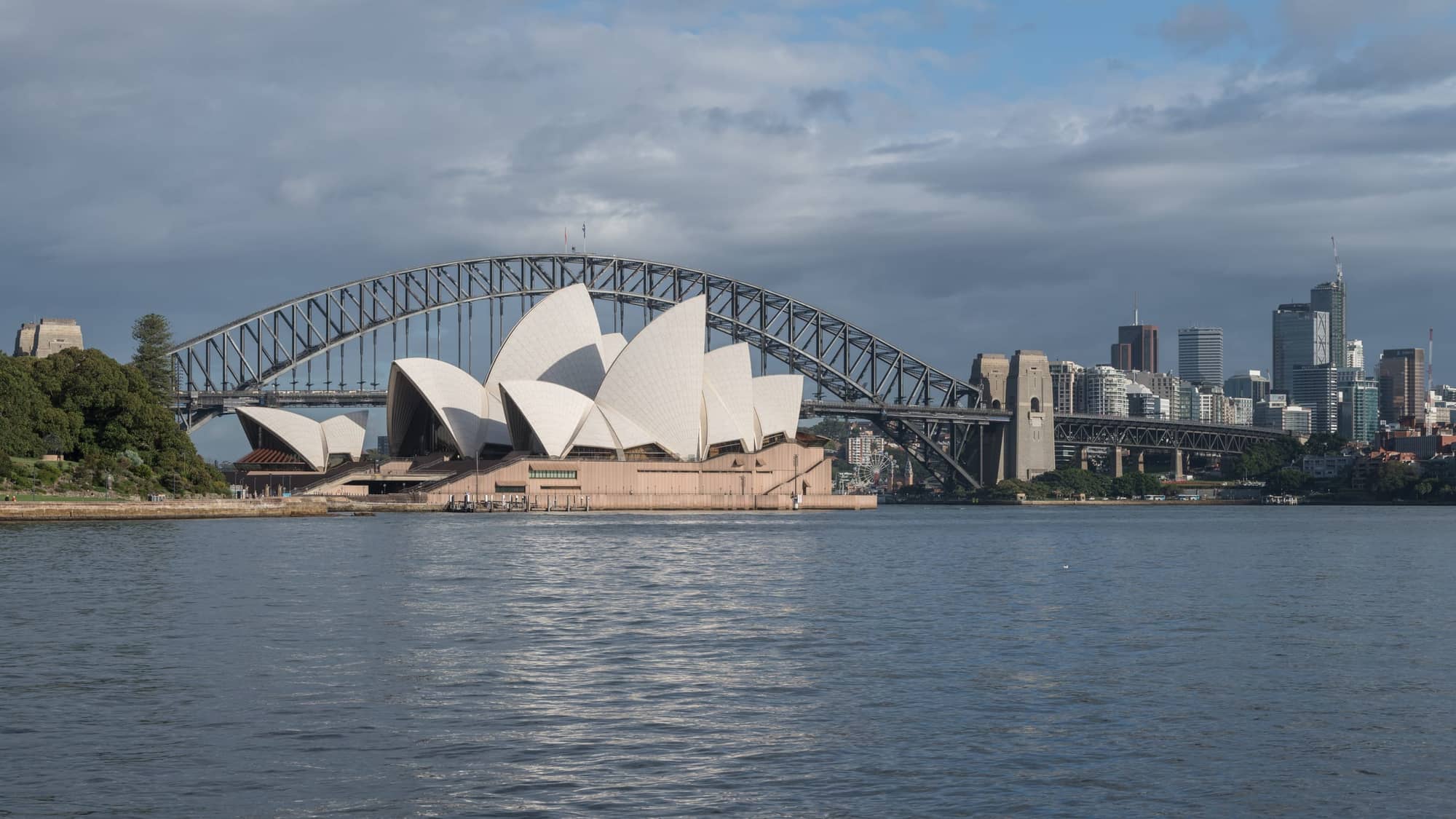 Sydney Opera House and Sydney Harbour Bridge across the harbour with the city skyline behind